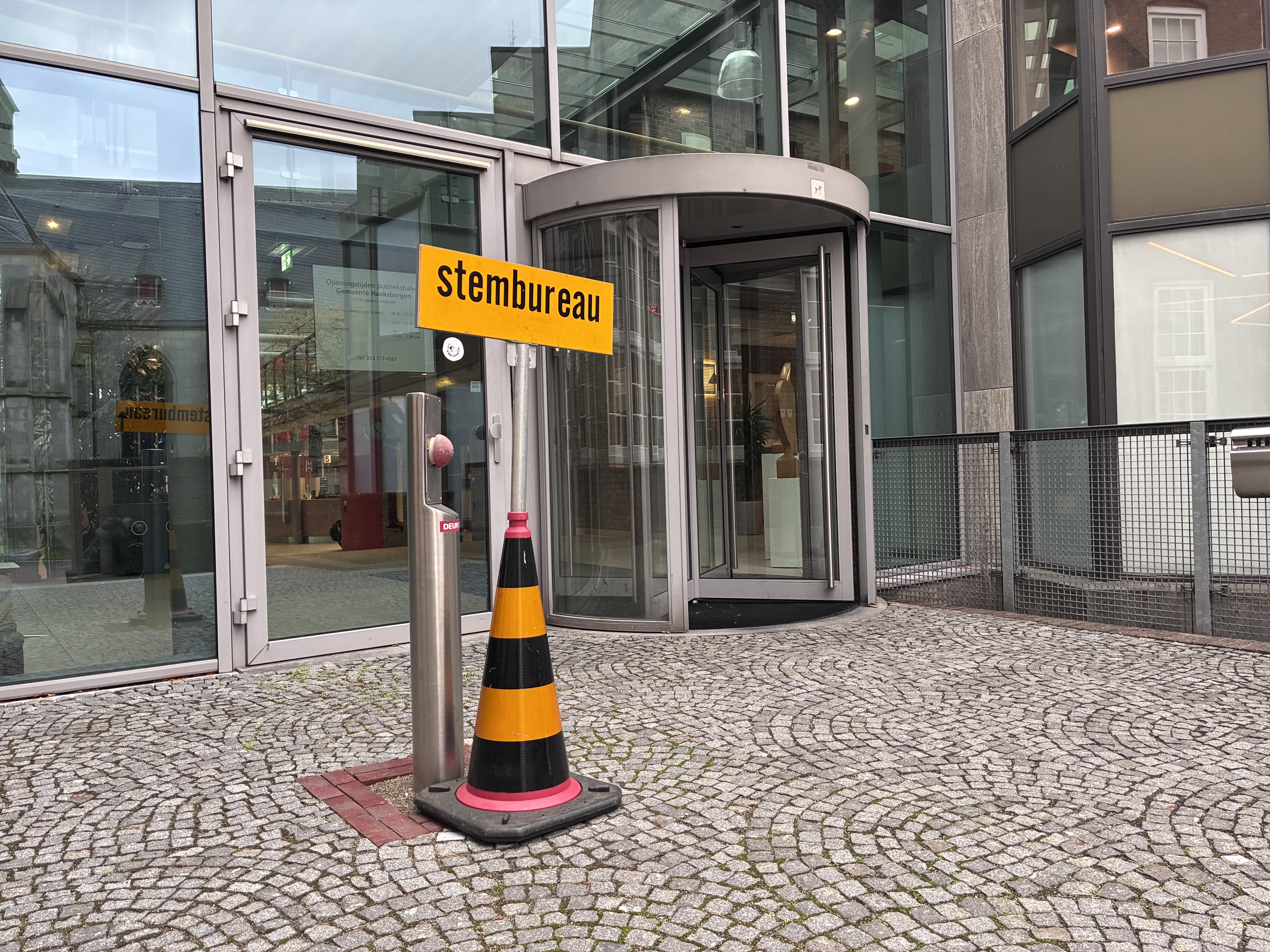 Foto van bord met de tekst stembureau bij ingang gemeentehuis. 