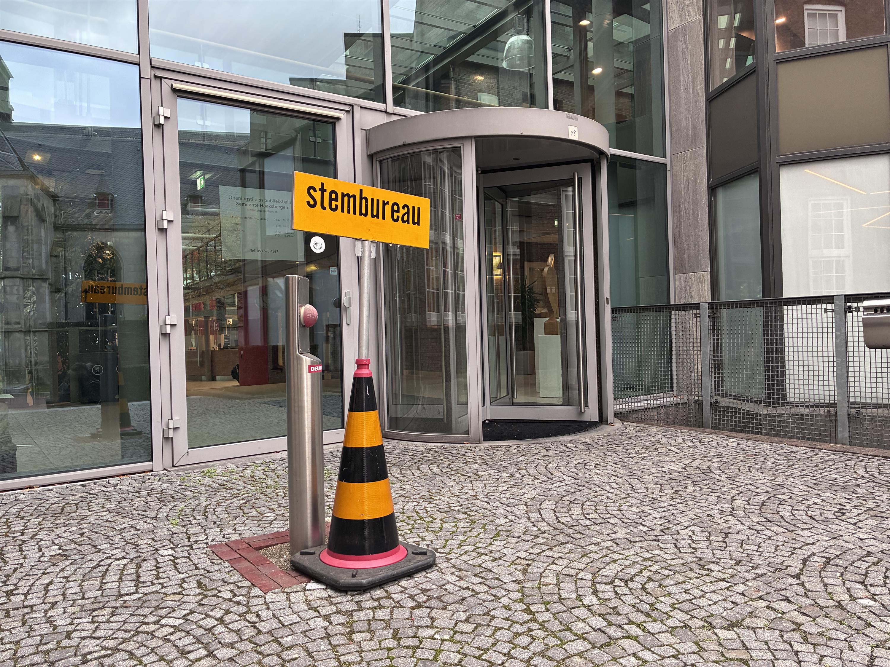 Foto van bord met de tekst stembureau bij ingang gemeentehuis. 