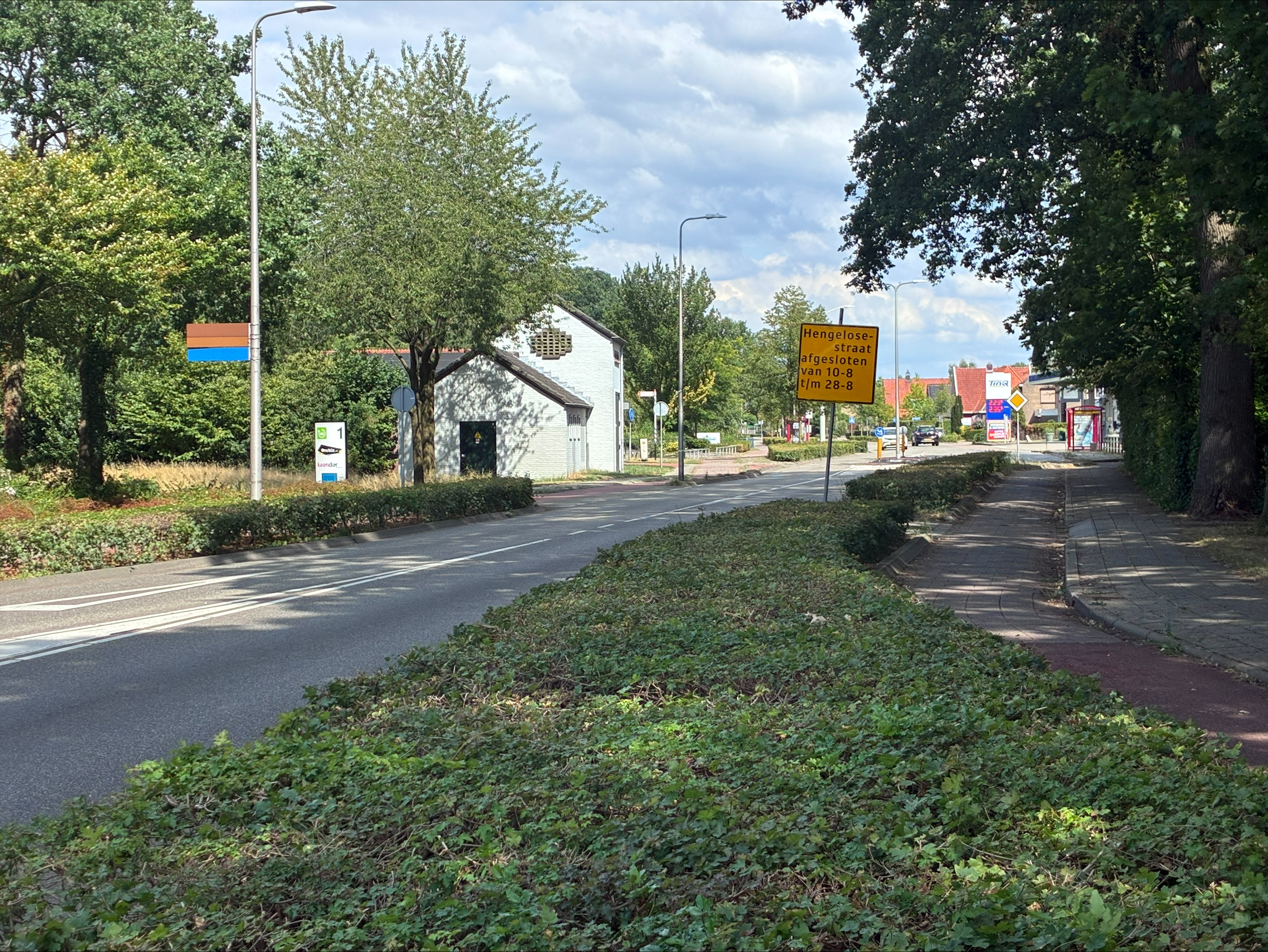 Blik de Hengelosestraat in ter hoogte van de Benninkrotonde waar een bord staat met aangekondigde wegwerkzaamheden. 