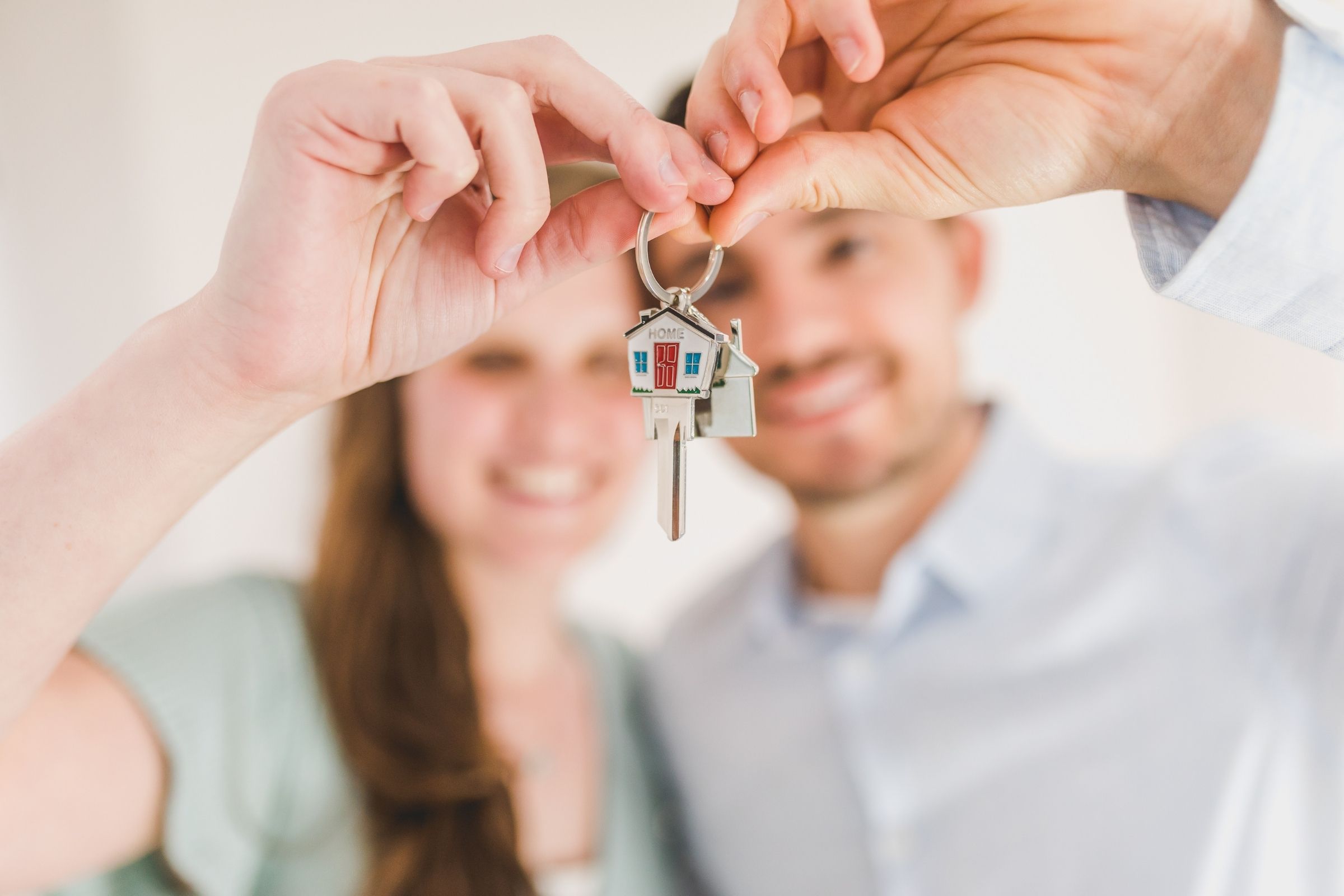 Jong stel houdt trots een huissleutel omhoog. Stockfoto.