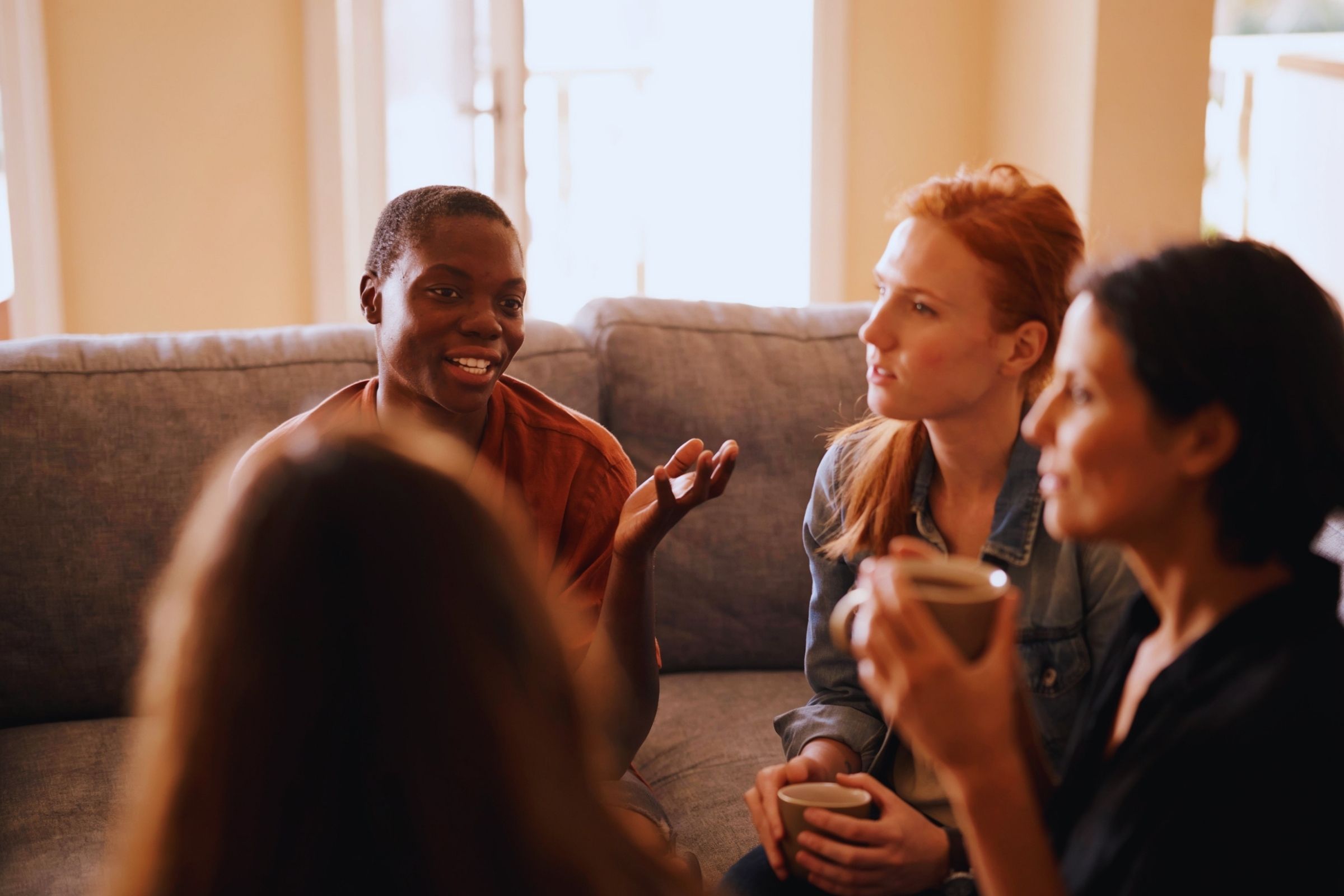 Vier vrouwen met elkaar in gesprek zittend in een kring.
