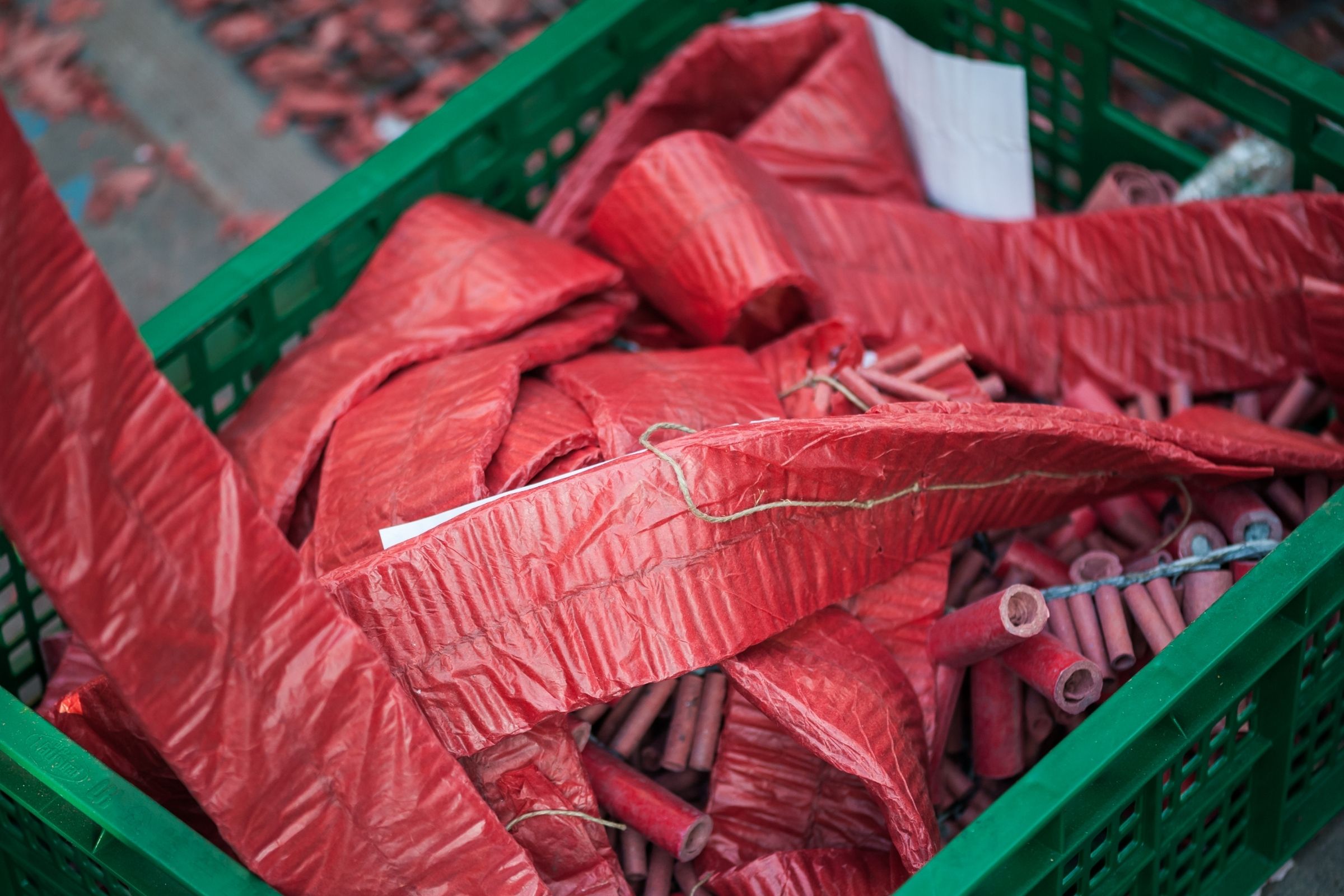 Rode vuurwerkrollen zoals duizendklappers bij elkaar in een groene krat.