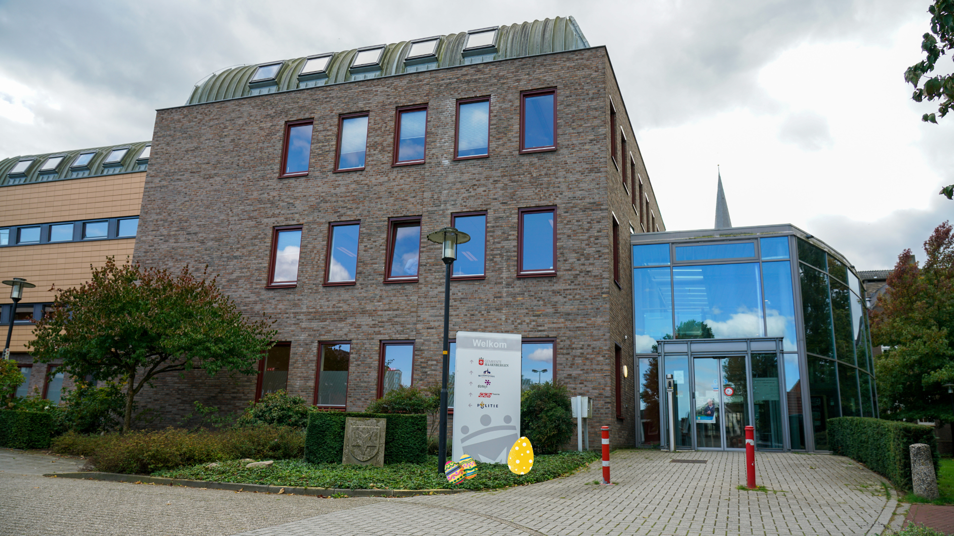 Foto van de ingang van het gemeentehuis aan de kant van de Blankenburgerstraat. Op de voorgrond liggen een paar paaseitjes. 