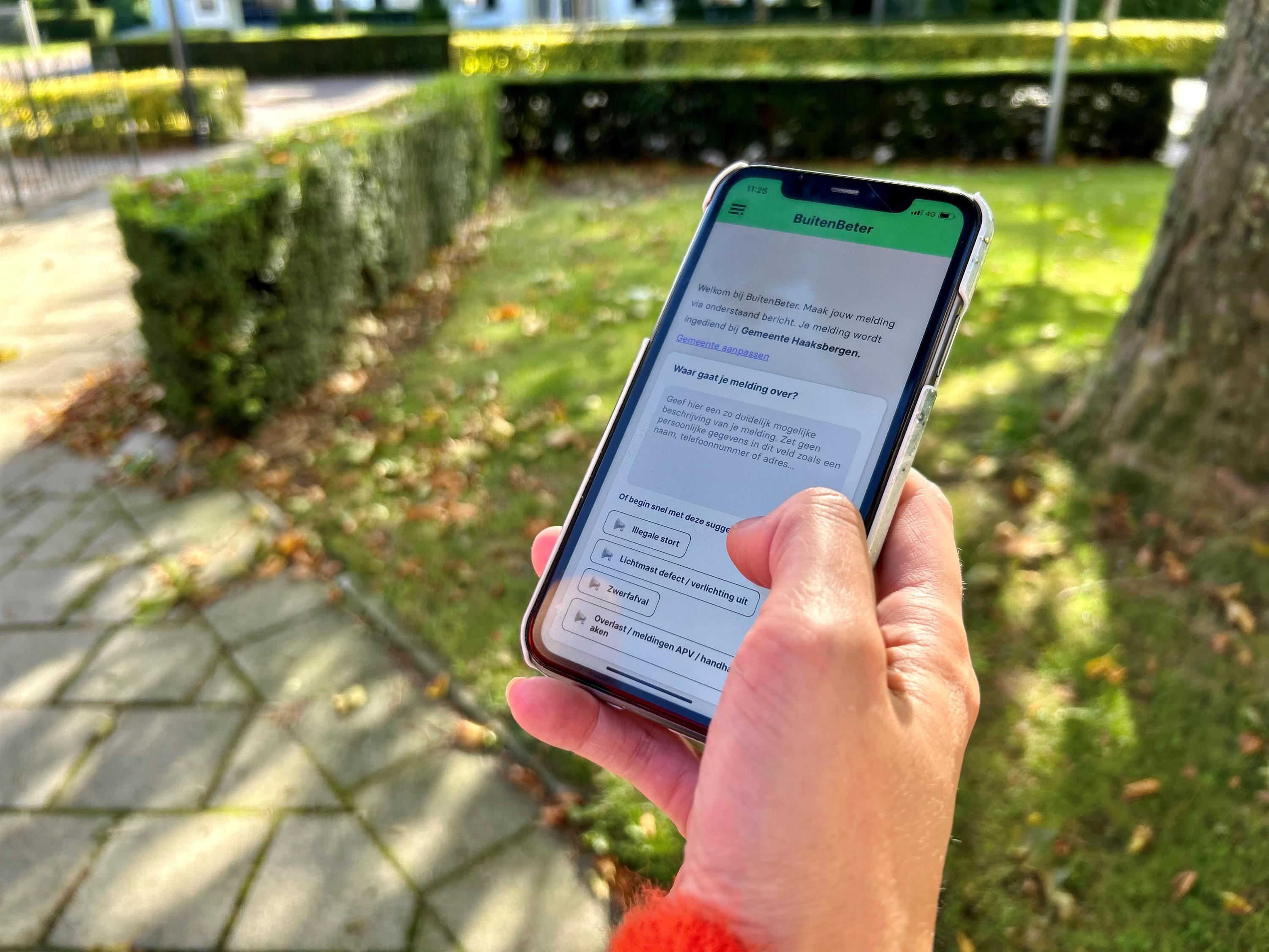 Hand met een smartphone waarop de app BuitenBeter open staat.
