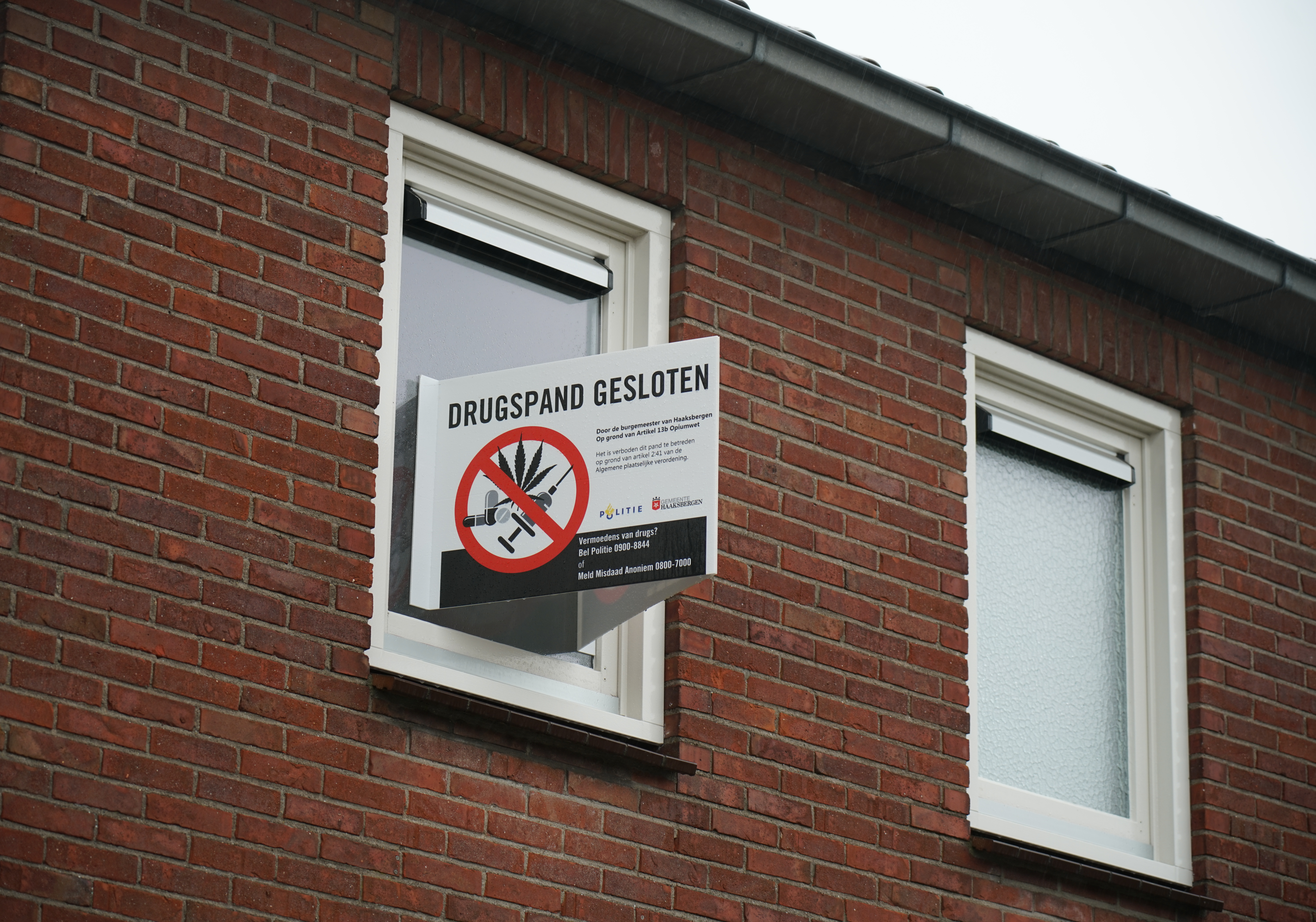 Raam met een bord dat het drugspand gesloten is. 