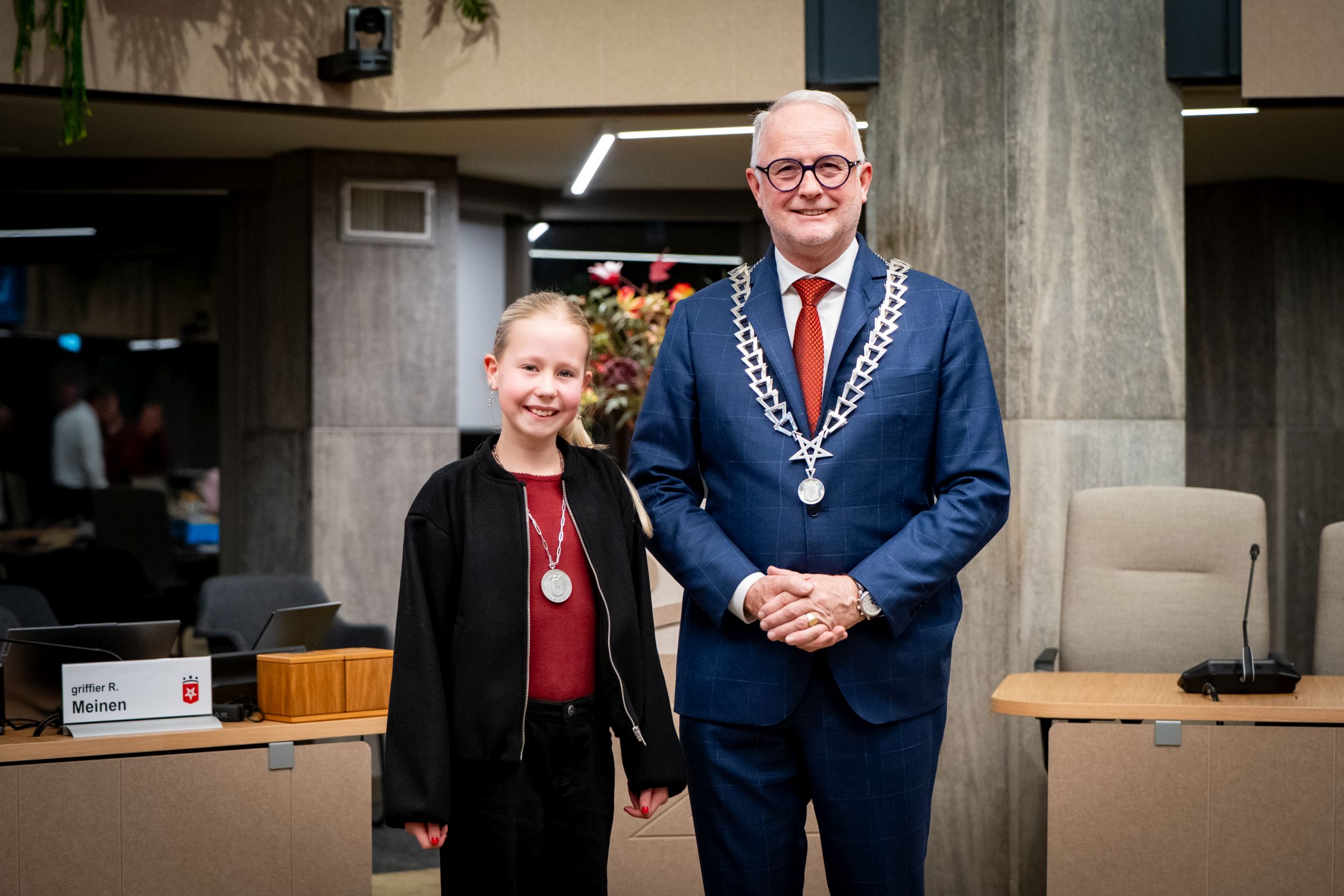 Foto: Kinderburgemeester Janna Winkelhorst en burgemeester Gerard van den Hengel naast elkaar. Beide met ambtsketen om de nek. 