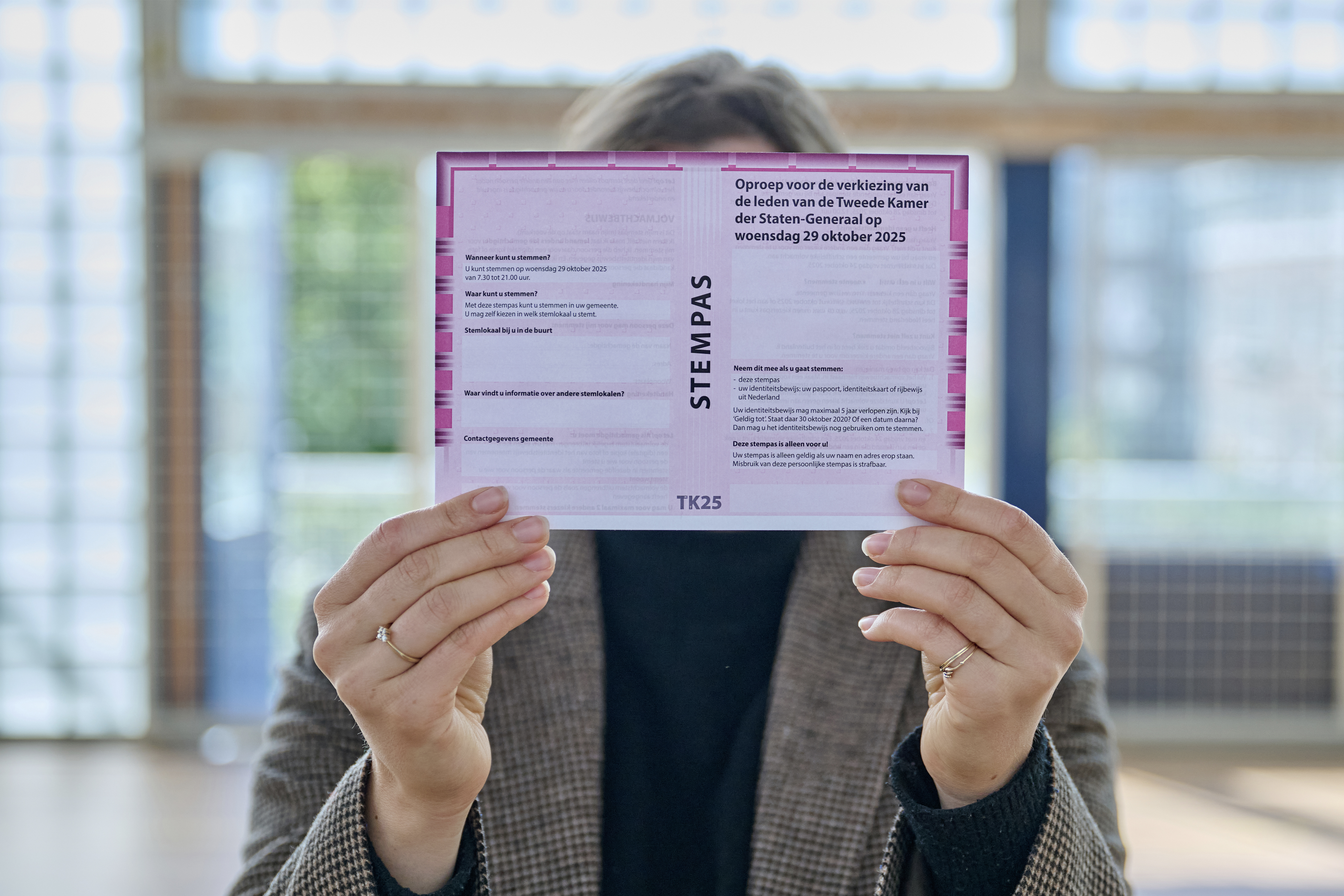 Persoon houdt stempas voor de Tweede Kamerverkiezingen 2025 omhoog 