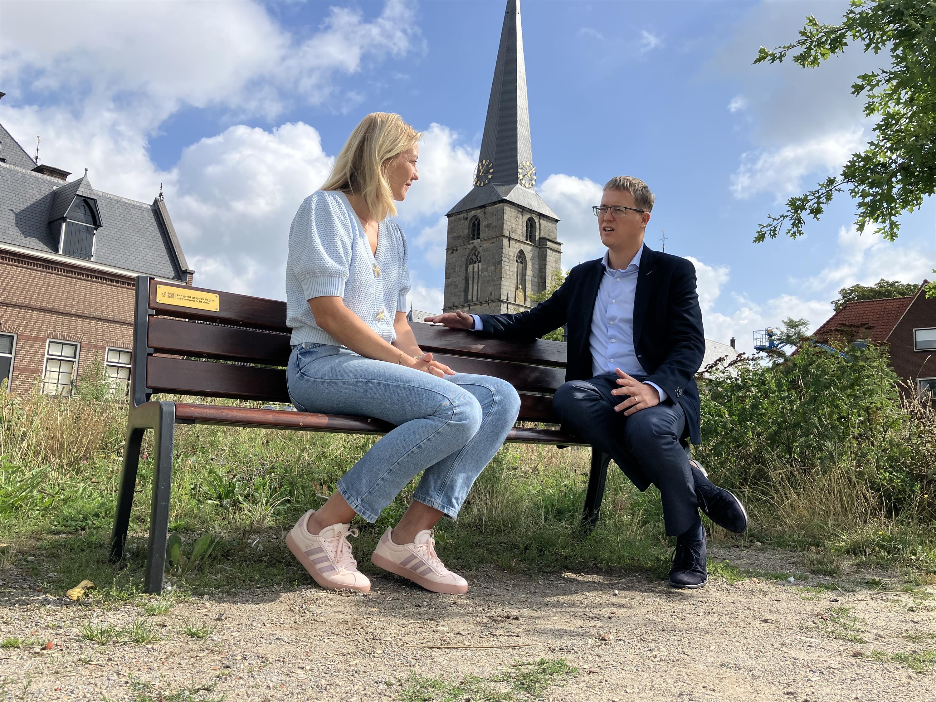 Beleidsmedewerker Suzanne Wienk en wethouder Thij Looman op een 1K Z13 J3 - bankje in Haaksbergen.