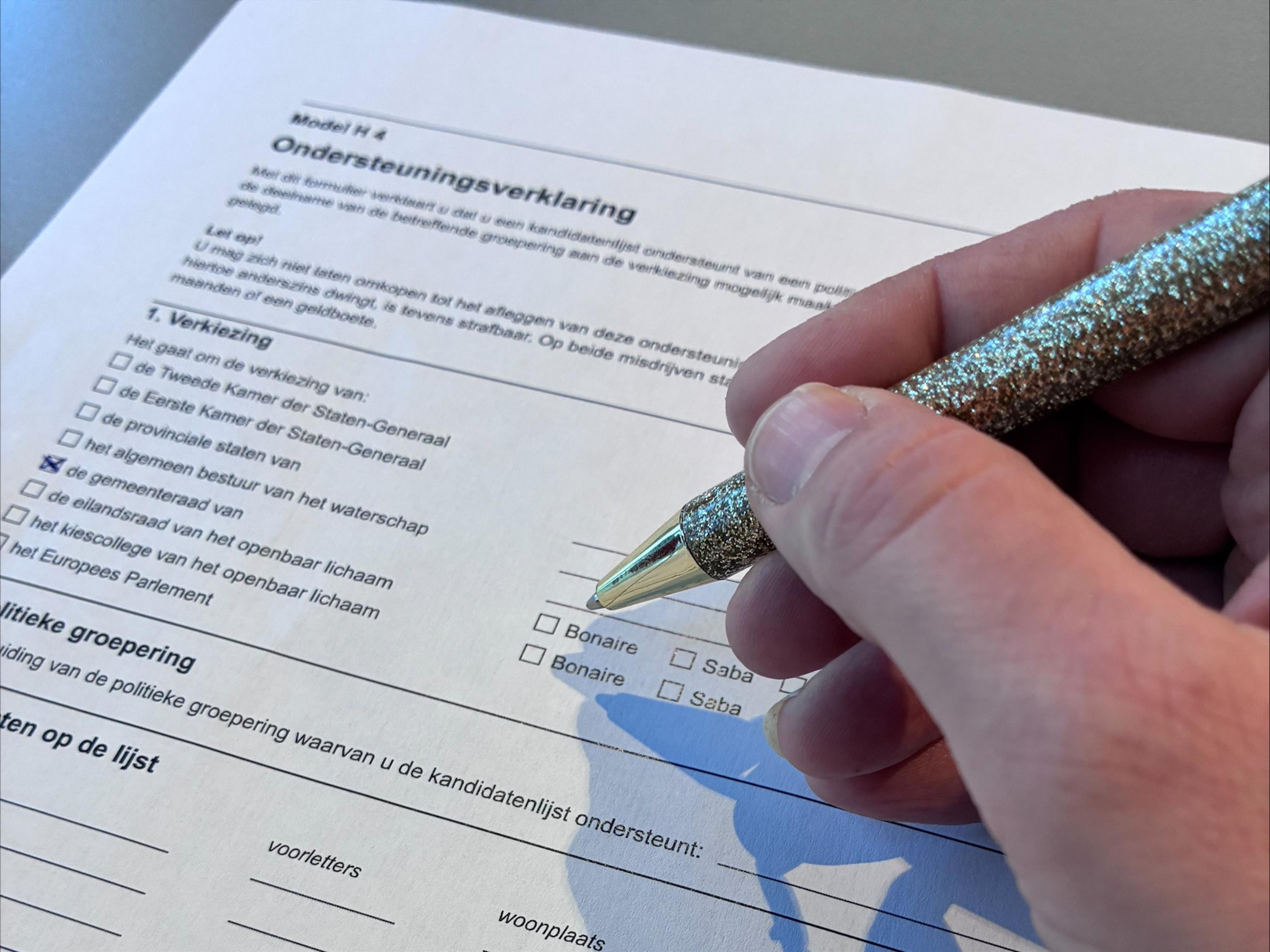 Foto van een hand met pen die een ondersteuningsverklaring invult.