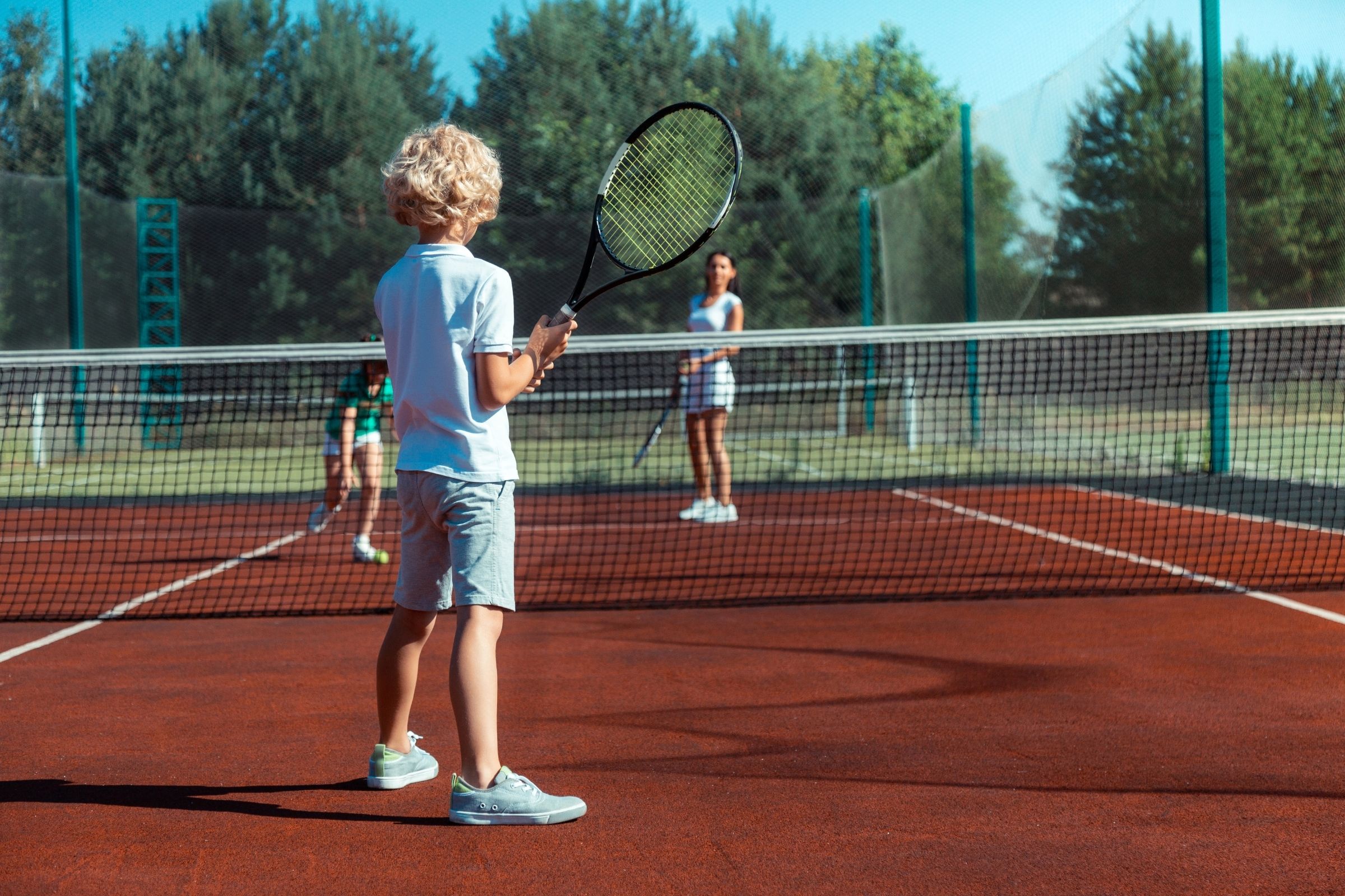 Kind met tennisracket op tennisbaan.