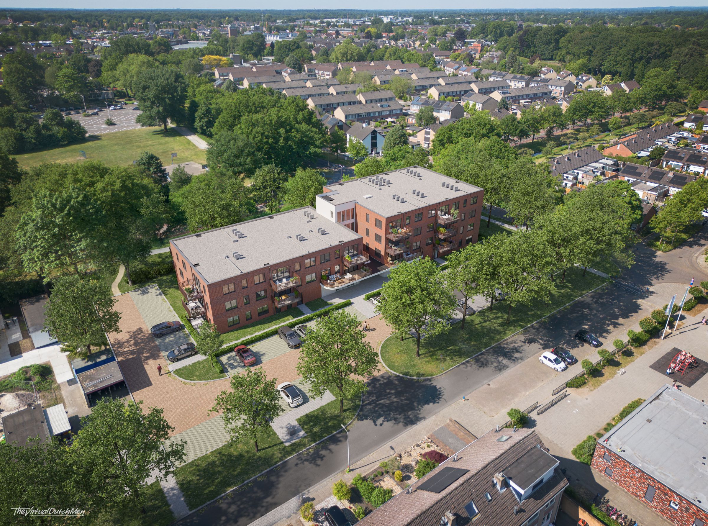 Appartementencomplex tussen bomen en huizen van bovenaf gefotografeerd.